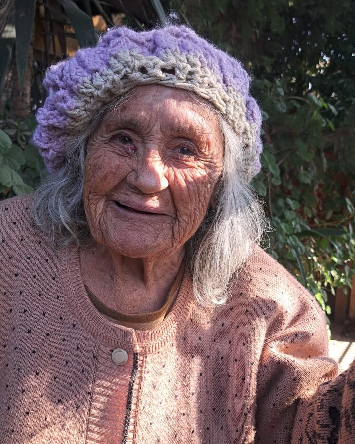 Adulta mayor con gorro tejido sonriendo al aire libre